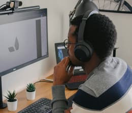 Picture of a student working on a laptop wearing Sony WH-1000XM4 headphones
