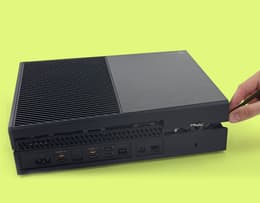The Xbox One right side up with an arrow showing the top panel opening like a pizza box