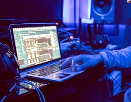 Apple MacBook Pro 14-inch M1 Pro (2021) sitting next to MIDI gear in a digital audio workstation setup.