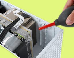 A person using compressed air on the Xbox Series S vents to clean internal components